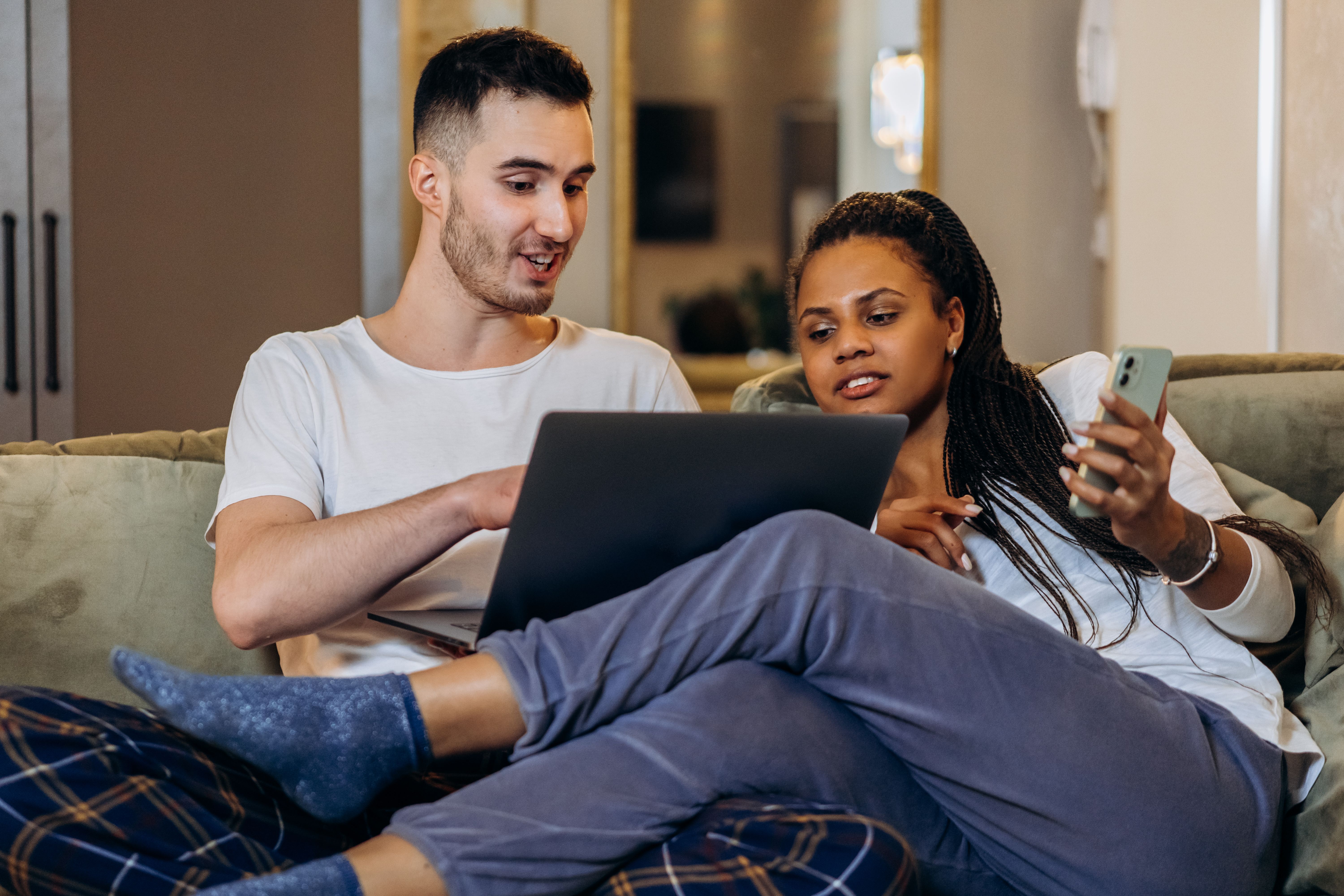 Couple reviewing bills at home on a laptop and phone